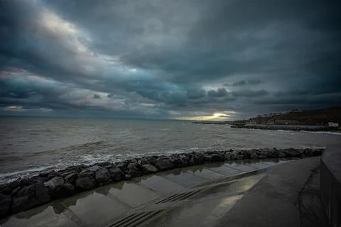 Dramatic sky over the black sea with waves, clouds and stones Stock Photos