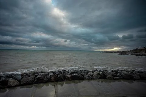 Dramatic sky over the black sea with waves, clouds and stones Stock Photos