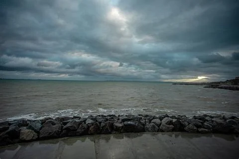 Dramatic sky over the black sea with waves, clouds and stones Stock Photos