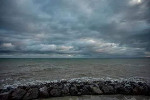 Dramatic sky over the black sea with waves, clouds and stones Stock Photos