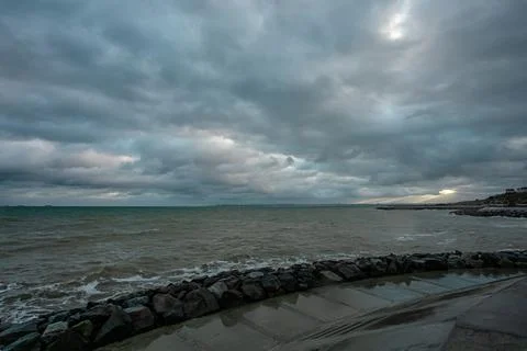 Dramatic sky over the black sea with waves, clouds and stones Stock Photos