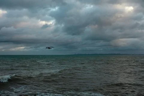 Dramatic sky over the black sea with waves, clouds and stones Stock Photos