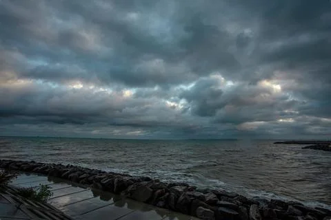 Dramatic sky over the black sea with waves, clouds and stones Stock Photos