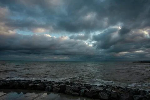 Dramatic sky over the black sea with waves, clouds and stones Stock Photos