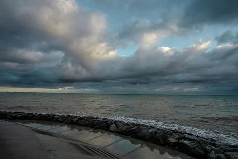 Dramatic sky over the black sea with waves, clouds and stones Stock Photos