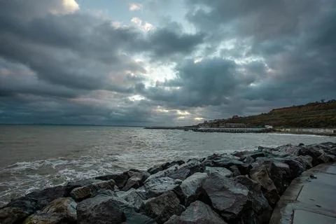 Dramatic sky over the black sea with waves, clouds and stones Stock Photos