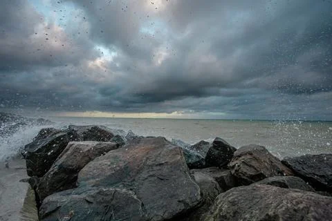 Dramatic sky over the black sea with waves, clouds and stones Stock Photos