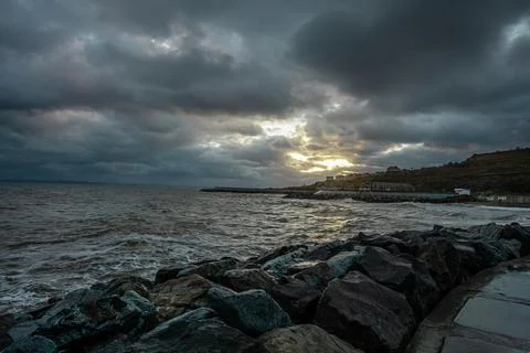 Dramatic sky over the black sea with waves, clouds and stones Stock Photos