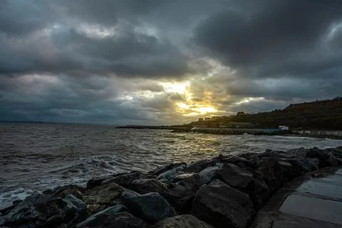 Dramatic sky over the black sea with waves, clouds and stones Stock Photos