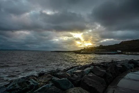 Dramatic sky over the black sea with waves, clouds and stones Stock Photos