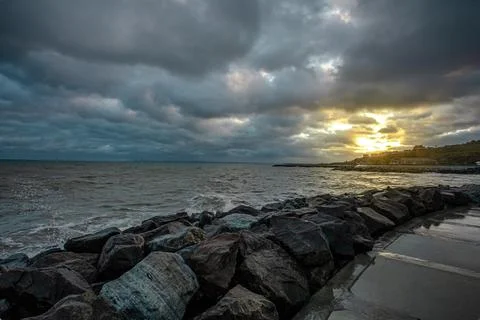 Dramatic sky over the black sea with waves, clouds and stones Stock Photos