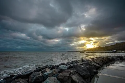 Dramatic sky over the black sea with waves, clouds and stones Stock Photos