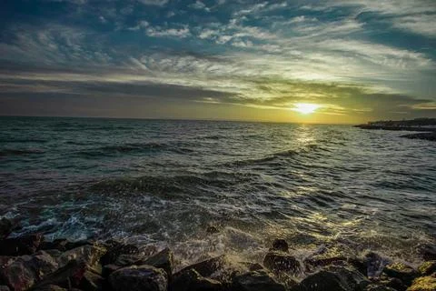 Dramatic sky over the black sea with waves, clouds and stones Stock Photos