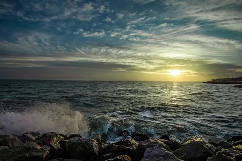 Dramatic sky over the black sea with waves, clouds and stones Stock Photos
