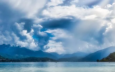 Dramatic Sky Over Lake and Mountains with Sun Rays Shining Through Clouds Stock Photos