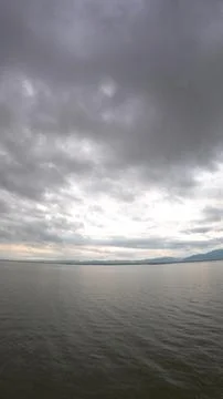 Dramatic sky over the lake with clouds and mountains in the background Stock Photos