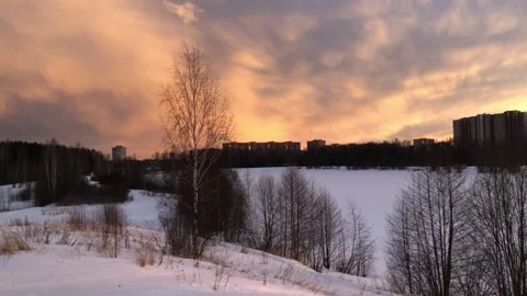 Dramatic sky over lake at sunset with town buildings silhouetted on horizon Stock Footage 149941766