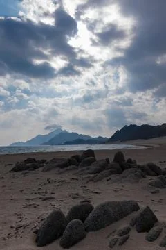 Dramatic Sky Over Oman Sadah Sandy Beach and Mountains Stock Photos