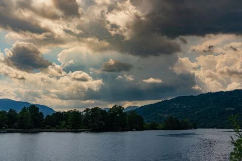 Dramatic sky over river with dark silhouette of land Stock Photos