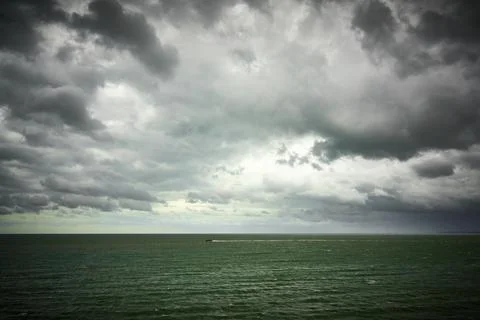 A dramatic sky over small boat on a green sea Stock Photos