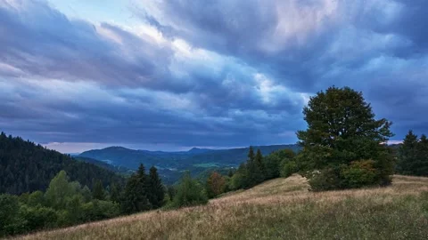 Dramatic sky with rain clouds on the horizon at dusk over a forest landscape on Vidéo 211864765