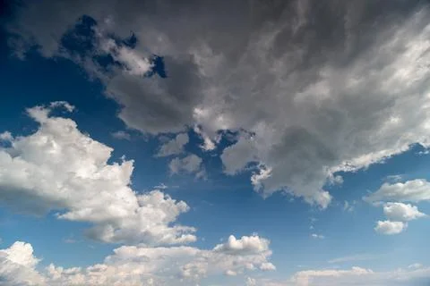 Dramatic sky with scattered cumulus clouds over blue horizon Stock Photos