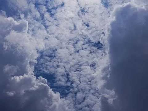 Dramatic sky scene where thick dark storm clouds begin to cover bright white clo Stock Photos