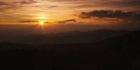 Dramatic sky with setting sun and silhouetted mountain ranges Stock Footage 103397940