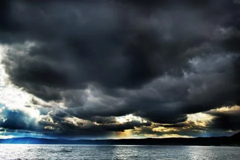Dramatic sky with stormy clouds and rain over the lake Stock Photos