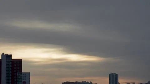 Dramatic sky with sun, moon and clouds above cityscape with construction cran Stock Footage 296315624