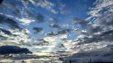 Dramatic sky with sunbeams breaking through dark clouds at sunset Stock Photos