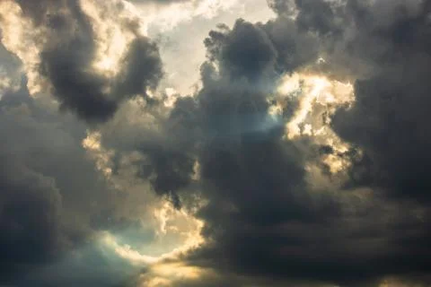 Dramatic sky with sunbeams shining through the clouds after a storm at sunset Stock Photos