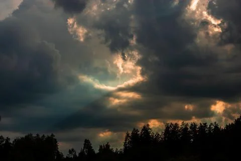Dramatic sky with sunbeams shining through the clouds after a storm at sunset Stock Photos