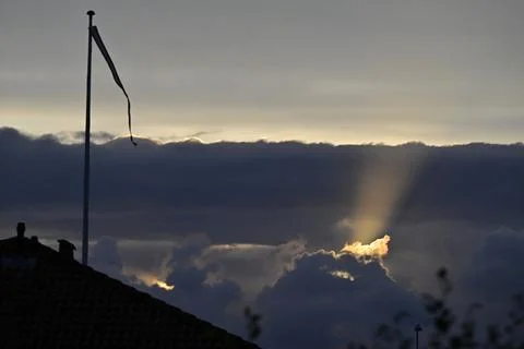 Dramatic Sky with Sunlight Rays and Flagpole Silhouette with Danish flag da.. Stock Photos
