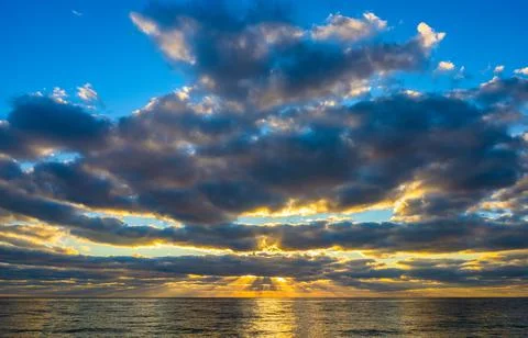 Dramatic sky at sunrise over ocean Stock Photos