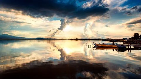 Dramatic sky at sunset on the lagoon with specular reflections on the water Stock Photos