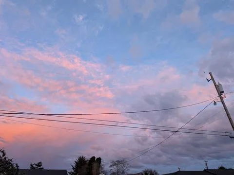 Dramatic sky with textured clouds and vibrant hues frames nearby power lines Stock Photos