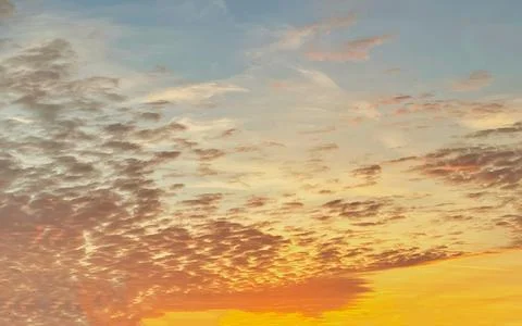 Dramatic sky with textured clouds at sunset with orange and pink hues Stock Photos