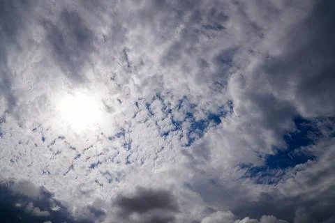 A dramatic sky with thick clouds partially covering the sun, creating a Stock Photos