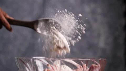 Dramatic slow motion closeup of flour thrown from a spatula into a glass bowl Stock Footage 132976335