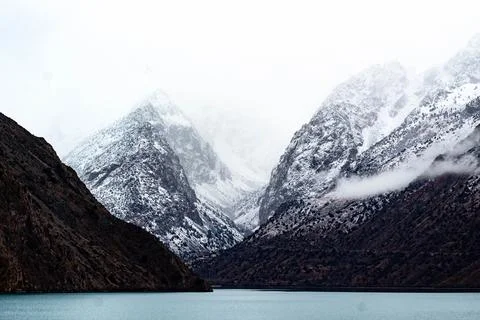 Dramatic Snow-Capped Mountains and Lake in a Misty Landscape Stock Photos
