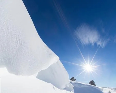 Dramatic Snowdrift Under Bright Sun and Clear Blue Winter Sky 스톡 사진