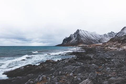 Dramatic snowy mountain ridge rises into heavy winter clouds in Lofoten, No.. Фото