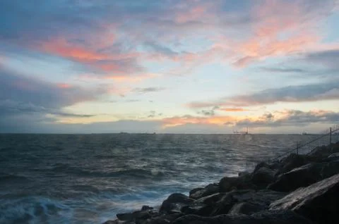 Dramatic splashing ocean wave in the evening with twilight sky in Winter at b Stock Photos