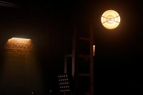 Dramatic stage lighting illuminates a dark industrial space with brick walls Stock Photos