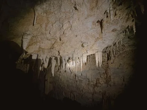 Dramatic stalactites and ancient rock formations illuminate the ceiling of .. Stock Photos