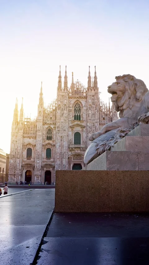 Dramatic stone lion statue in the foreground with Milan Cathedral behind 스톡 동영상 344100174