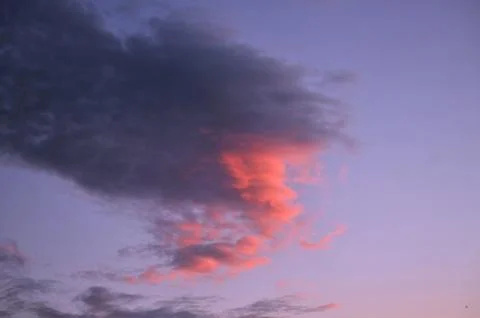 Dramatic storm cloud illuminated by pink sunset light Foto stock