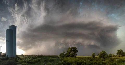  A dramatic storm cloud looms over a rural landscape with a blue water tow... Stock Photos