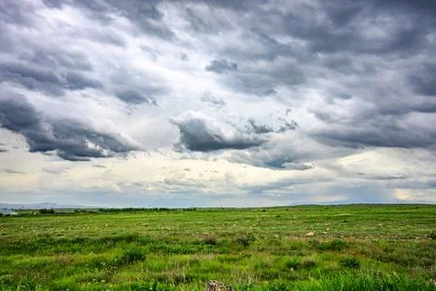 Dramatic storm clouds above endless green field Foto stock